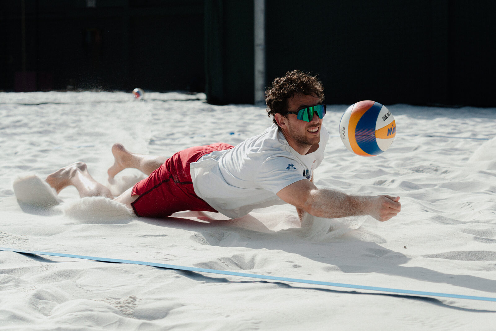 A player dives to dig the ball in the sand during a training session
