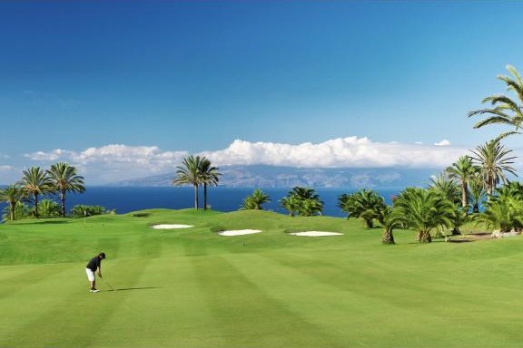 A player on the green at Abama Golf with palms and the sea beyond